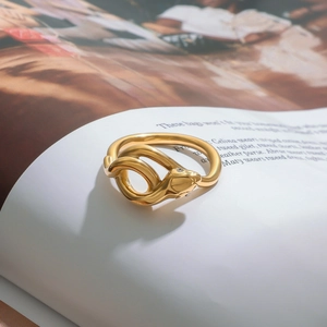 Elegant gold snake-shaped stainless steel ring with subtle diamond accents on a magazine