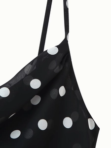 Close-up of black and white polka dot dress with delicate straps and ruffled neckline