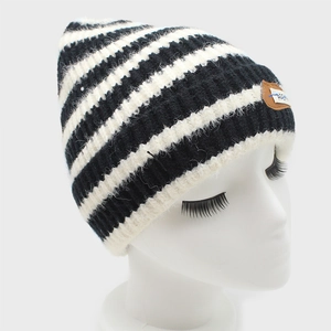 Detail of black and white striped knit beanie with premium brown leather logo patch