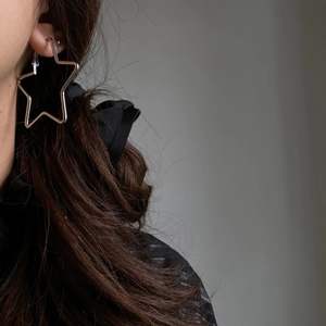 Close-up of minimalist silver hollow star hoop earrings worn by a model in a modern style