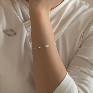 Close-up of minimalist silver chain bracelet with round bead on model's wrist