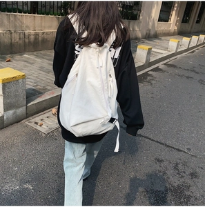 Street style view showing the back of a white washed canvas backpack for women and men