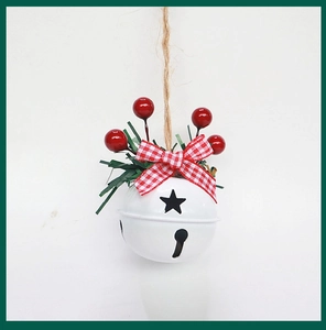 Close-up of white metal Christmas bell with star cutouts, red berries and pine needles
