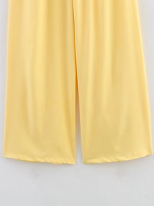Close-up of vibrant yellow wide-leg trousers with smooth draping fabric for women