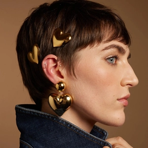 Close-up of golden heart hair clips and matching earrings on a stylish denim jacket model