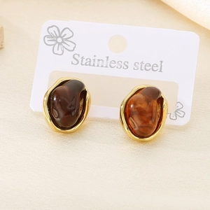 Macro detail of amber resin earrings on stainless steel cards with gold finish