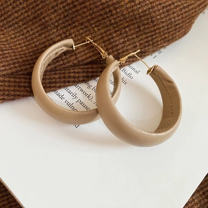 Macro shot of beige leather wrapped round hoop earrings with golden metal hooks