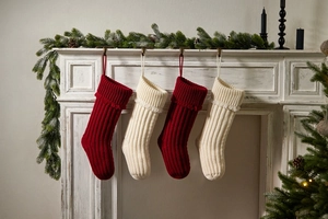 Detail of red and white chunky knit Christmas stockings on a festive fireplace mantle