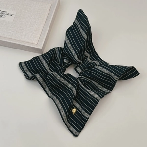 Détail d'un chouchou en tissu à rayures bleues avec une petite breloque en forme de cœur