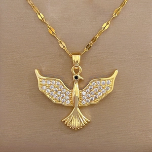 Macro shot of gold bird pendant with clear zircons on delicate chain over silk fabric
