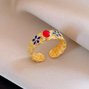 Macro detail of French vintage open ring with red oval stone and blue floral enamel pattern