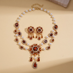 Vintage gold baroque jewelry set with pearls and amber stones on textured background