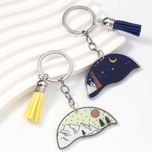 Detail view of colorful enamel day and night landscape keychains with suede tassels
