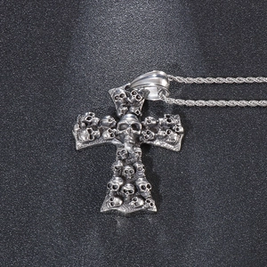 Close-up of silver punk cross pendant with detailed skull reliefs on a metal rope chain