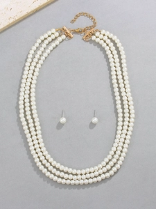 Détail du collier de perles crème à trois couches avec boucles d'oreilles assorties