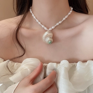 Detail of baroque pearl necklace with a large natural shell pendant on neck