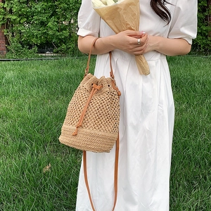 Chic woven paper straw bucket bag with drawstring closure and slim shoulder straps