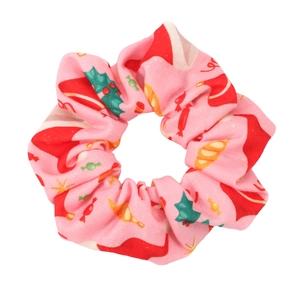 Close-up of pink Christmas scrunchie with festive patterns of Santa hats and candy canes