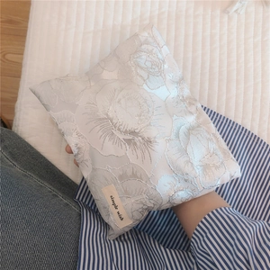 Detail of elegant gold-wire rose jacquard fabric on a white small cosmetic pouch