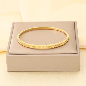 Primo piano della trama geometrica con cristalli incastonati sul bracciale oro.