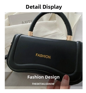 Detail of a black hourglass handbag with golden FASHION logo and metallic handle joints