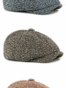 Gros plan de casquettes gavroche en tweed texturé en bleu, marron et orange empilés
