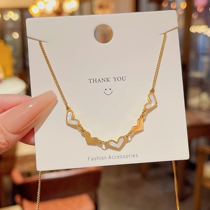 Detailed close-up of golden heart pendant necklace with alternating shells on white card