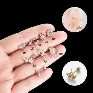 Set aus 8 goldenen Blumen-Ohrsteckern mit Zirkon auf der Hand und am Ohr gezeigt