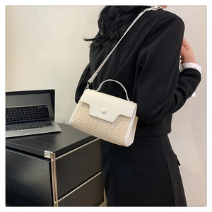 Détail du sac à main minimaliste en paille et similicuir blanc porté par un mannequin