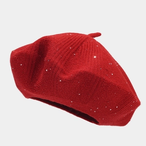 Close-up of red knitted beret featuring silver sequins and soft woolen texture