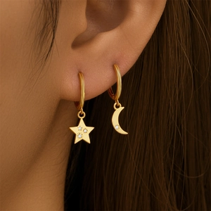 Detailed close-up of gold star and moon earrings with sparkling crystals on ear lobe