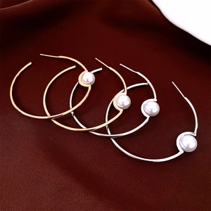 Close-up of gold and silver large hoop earrings with pearls on silk background