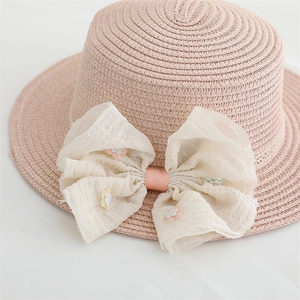 Vue détaillée d'un chapeau en paille rose avec un grand nœud en mousseline brodée de fleurs