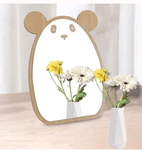 Detail of panda-shaped wooden desk mirror reflecting white flower vase on wooden surface