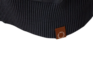 Detail of dark grey ribbed knit hem with a round brown vintage decorative label