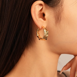 Minimalist gold twisted C-shape hoop earrings with irregular wrinkled molten texture