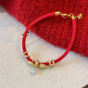 Détail du bracelet en corde rouge tressée avec perles dorées et pendentif opale