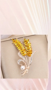 Macro shot of rose gold wheat brooch with yellow marquise stones and pearl