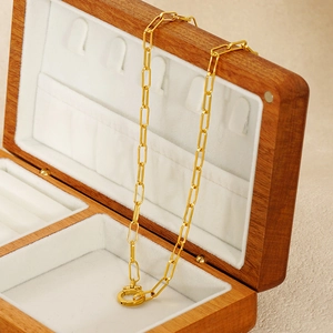 Detail of gold paperclip chain necklace displayed on a luxury wooden jewelry box
