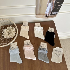 Detail of cotton crew socks with lace ruffle trim and bow accents in six soft colors