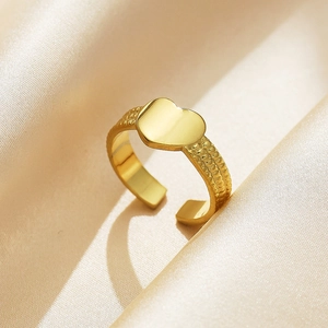 Detailed view of an 18k gold plated stainless steel heart ring on soft silk fabric