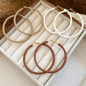 Detail of three pairs of large geometric leather wrapped hoop earrings in neutral tones