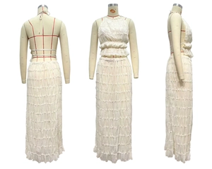 Detail of the white two-piece set featuring a halter crop top and layered tiered maxi skirt