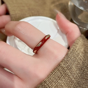 Macro detail of red enamel ring with gold leaf accents on a woman's finger