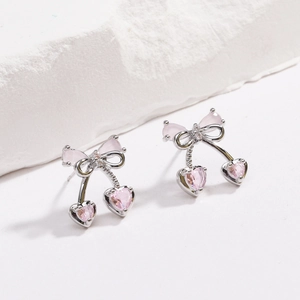 Vista macro degli orecchini a fiocco in argento con zirconi a cuore rosa e ciliegie