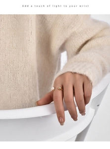 Detail of golden open ring with white pearl and gold bead on model finger