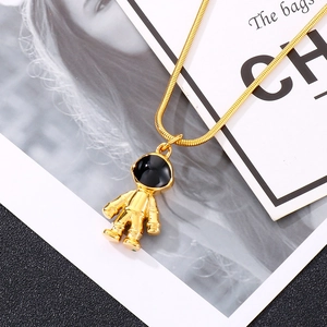 Close-up of golden astronaut pendant with black visor on elegant snake chain necklace