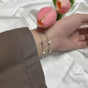 Detail of silver double-layer bracelet with star pendant and beads on a wrist