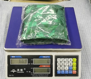 Detail showing a bright green glitter Christmas stocking decoration being weighed on a scale
