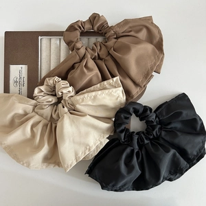 Close-up of pleated satin scrunchies in brown, beige and black on a jewelry tray